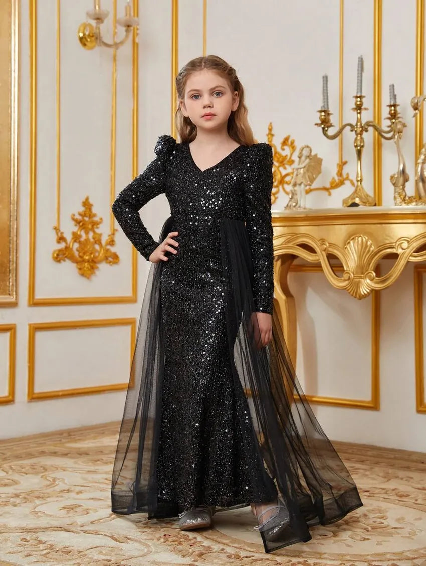 Side angle of black sequin dress for girls with tulle skirt overlay and glitter accents.