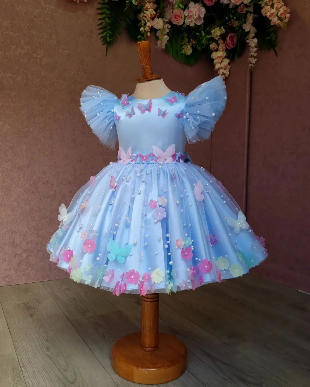 Front view of pastel blue butterfly dress with floral and pearl details for girls.