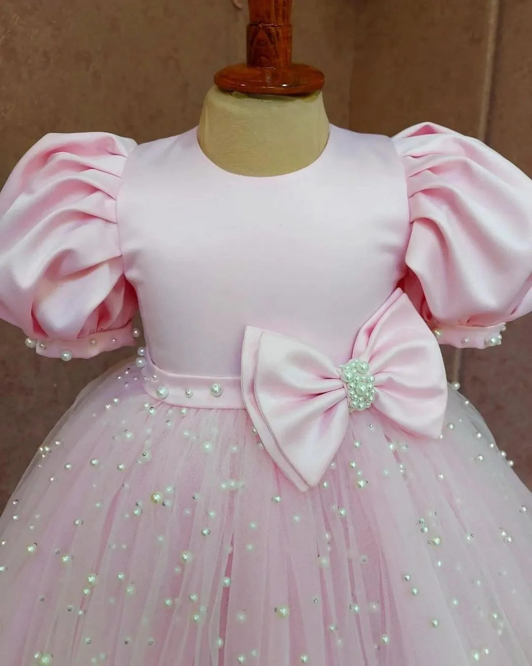 Close-up of the pearl-embellished bodice and delicate puff sleeves on a pink dress for girls, emphasizing the intricate detailing.