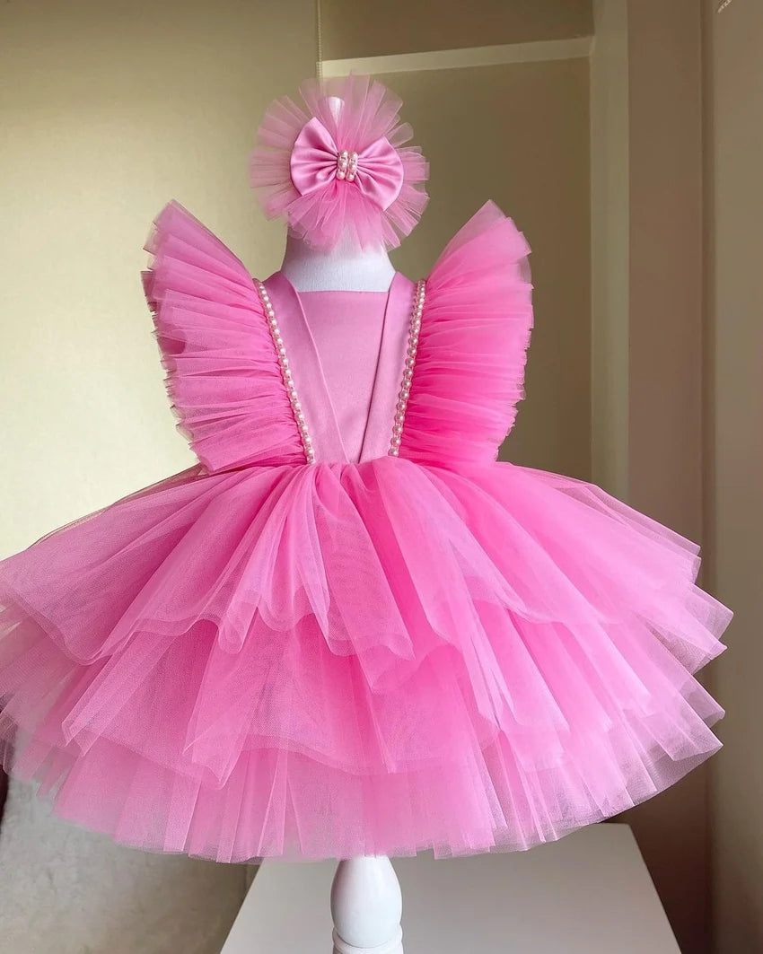 Close-up of floral details on the bodice of a pink tulle dress, highlighting the intricate flower accents and fine tulle fabric.