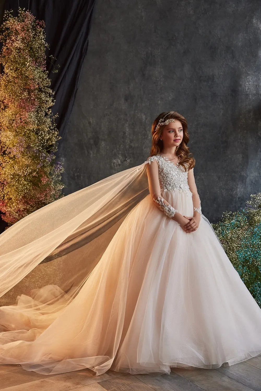 Side profile of ivory flower girl gown featuring long sleeves and cape