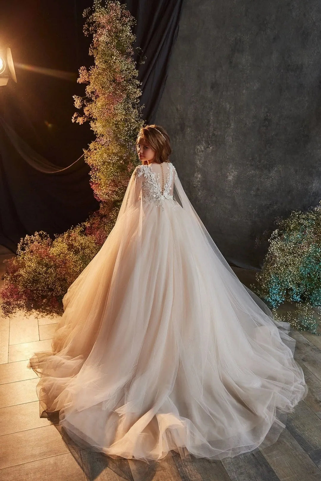 Back view of ivory flower girl dress with long train and cape