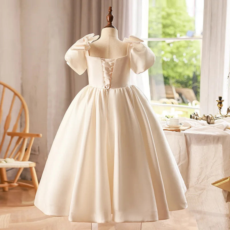  Back view of an ivory satin ball gown for girls, showcasing the smooth satin finish and tailored design.