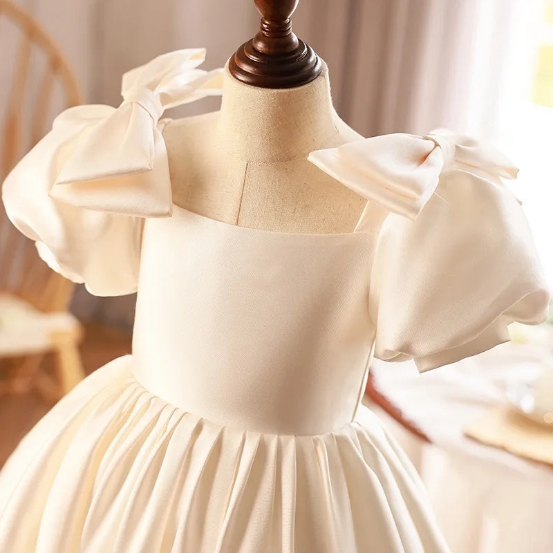 Close-up of the puff sleeves and fine satin detailing on an ivory ball gown for girls, emphasizing the high-quality fabric and craftsmanship.