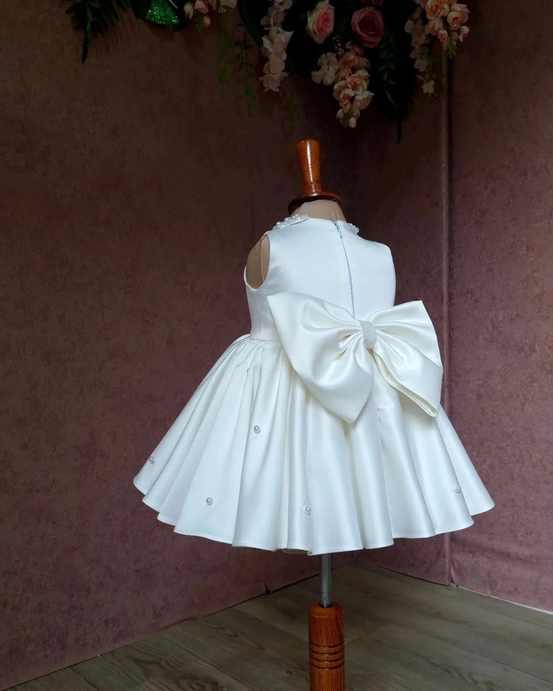 Back view of a white satin girls' dress showcasing a simple and refined design, ideal for formal events.