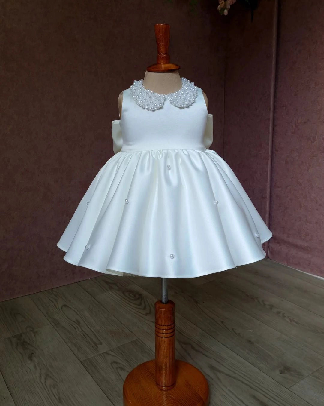 Front view of a white satin dress with an elegant pearl-embellished collar, perfect for baptisms and special occasions.