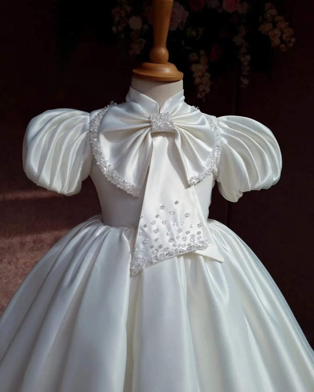 Close view of an elegant ivory satin girls' dress with a classic, smooth satin finish.