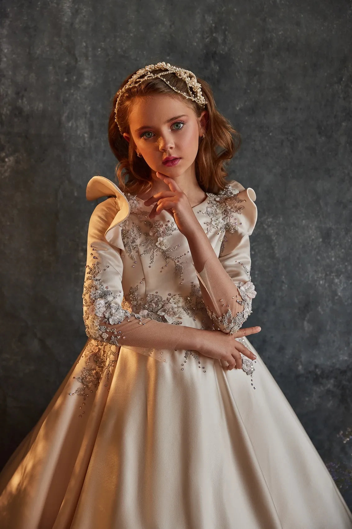 Close-up view of delicate rehinestones detailing on the bodice of a girls' satin formal dress, highlighting the luxurious texture and craftsmanship.