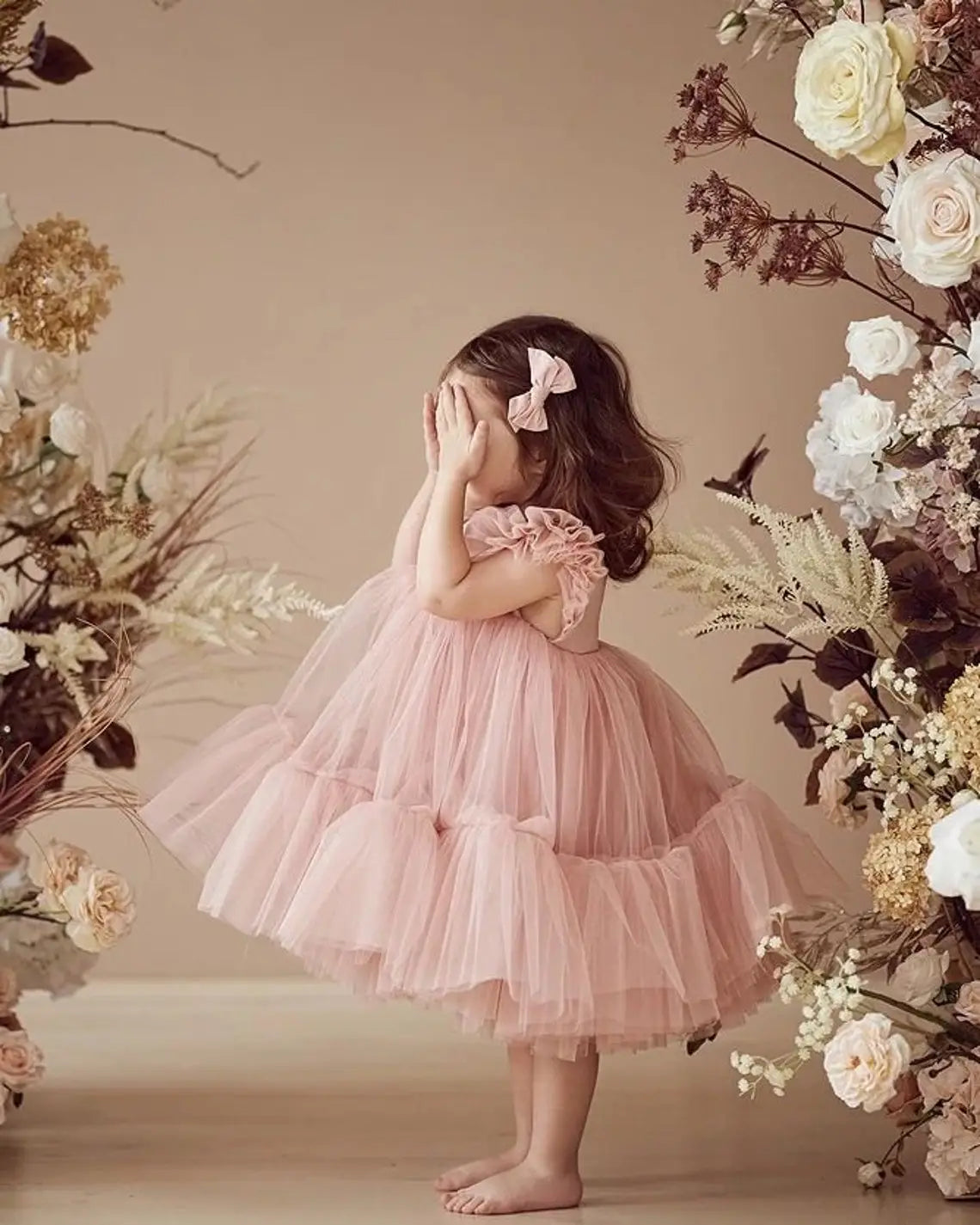 Back view of elegant blush pink toddler dress with tulle and ruffle details.