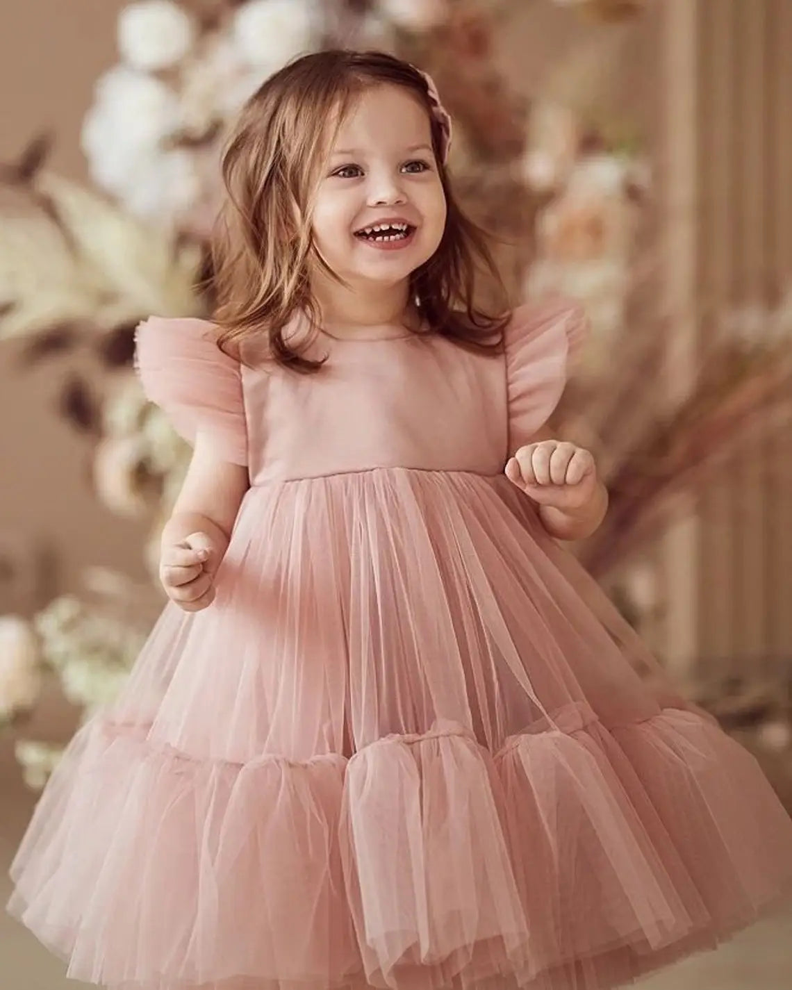 Close-up of soft tulle and ruffle sleeves on blush pink toddler flower girl dress.